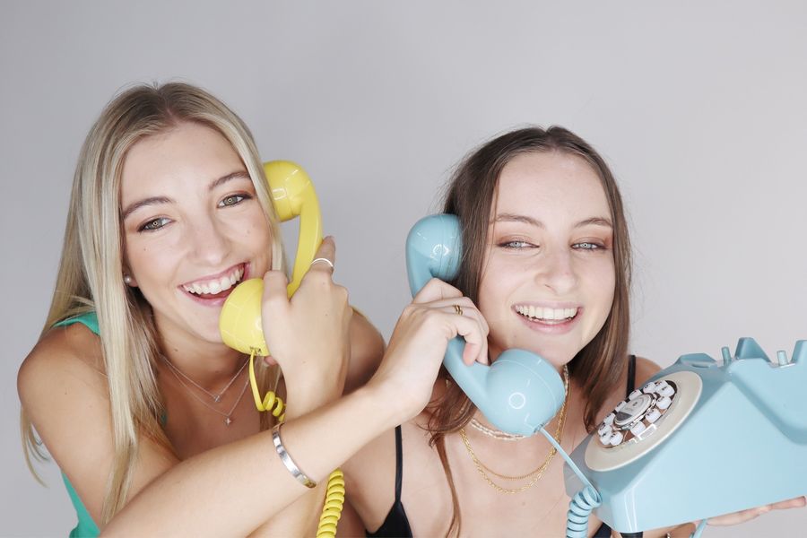 Two friends laugh on the blue and yellow retro phones